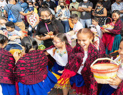 Young children in typical dresses for Ecuadorian National day holding baskets.